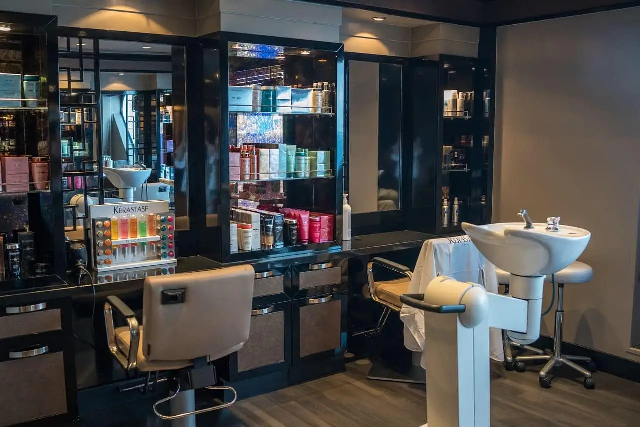 En modern frisörsalong med en stylingsstation, inklusive en stol, spegel, och hyllor fyllda med produkter.